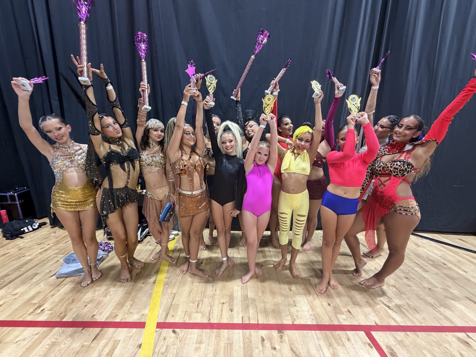 Studio dancers raising trophies at the True Dancer Championships